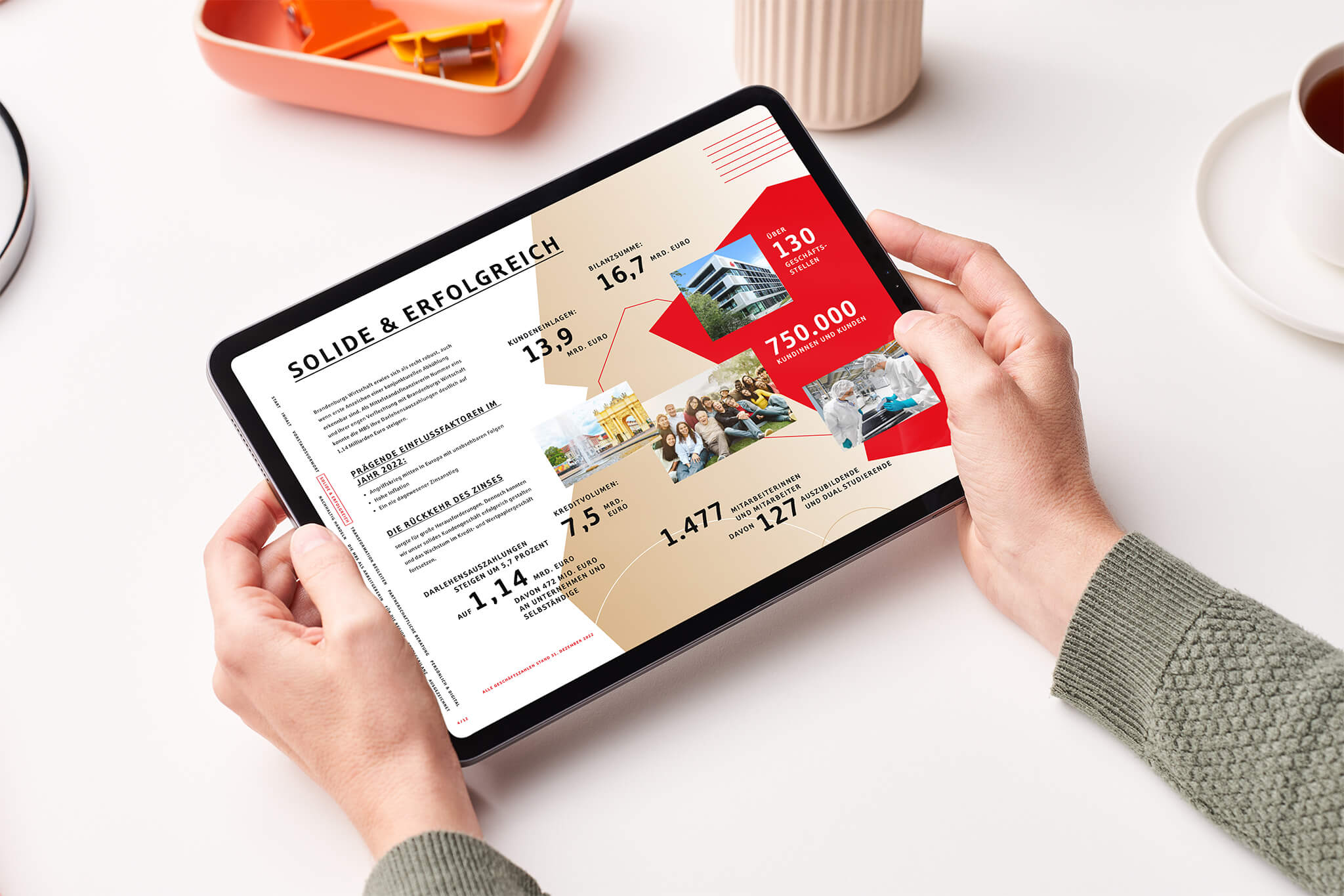 Ein Tablet wird von zwei Händen gehalten. Das Tablet zeigt die Web-PDF der Mittelbrandenburgischen Sparkasse..