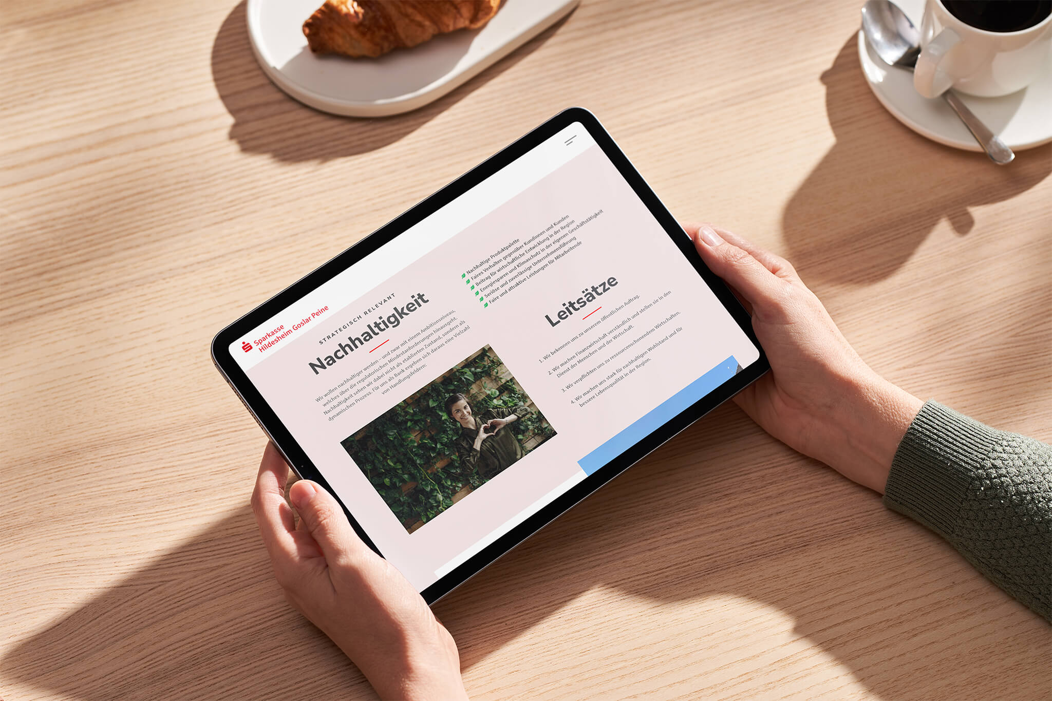 Ein Tablet wird von zwei Händen gehalten. Das Tablet zeigt den Onlinejahresbericht der Sparkasse Hildesheim Goslar Peine.