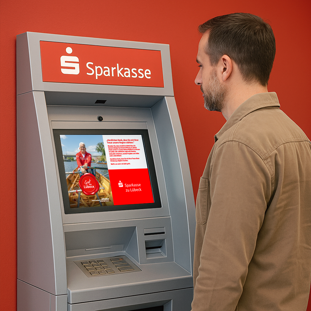Ein Kunde steht vor dem SB-Terminal in der Sparkasse und batrachtet die "Gut-für-Lübeck" Anzeige auf dem Screen