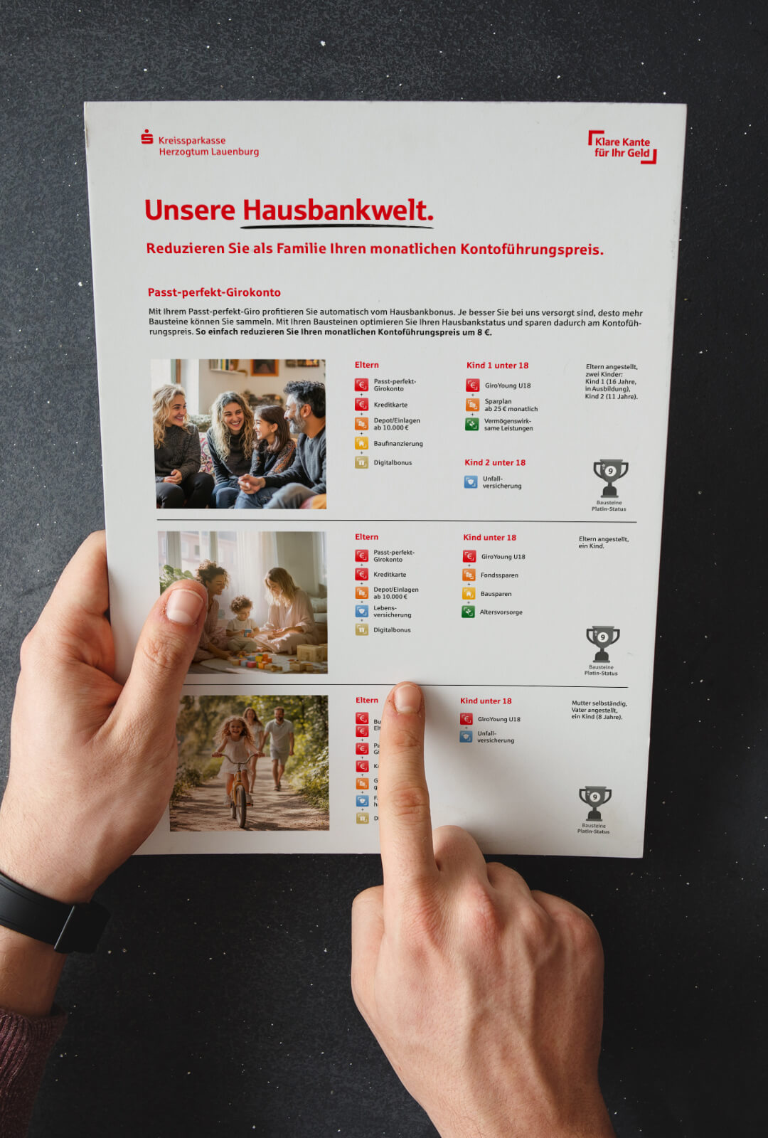 Eine männliche Hand hält das kompaktes Informationsblatt zur Hausbankwelt der Kreissparkasse Herzogtum Lauenburg und deutet mit einem Finger auf ein Detail.