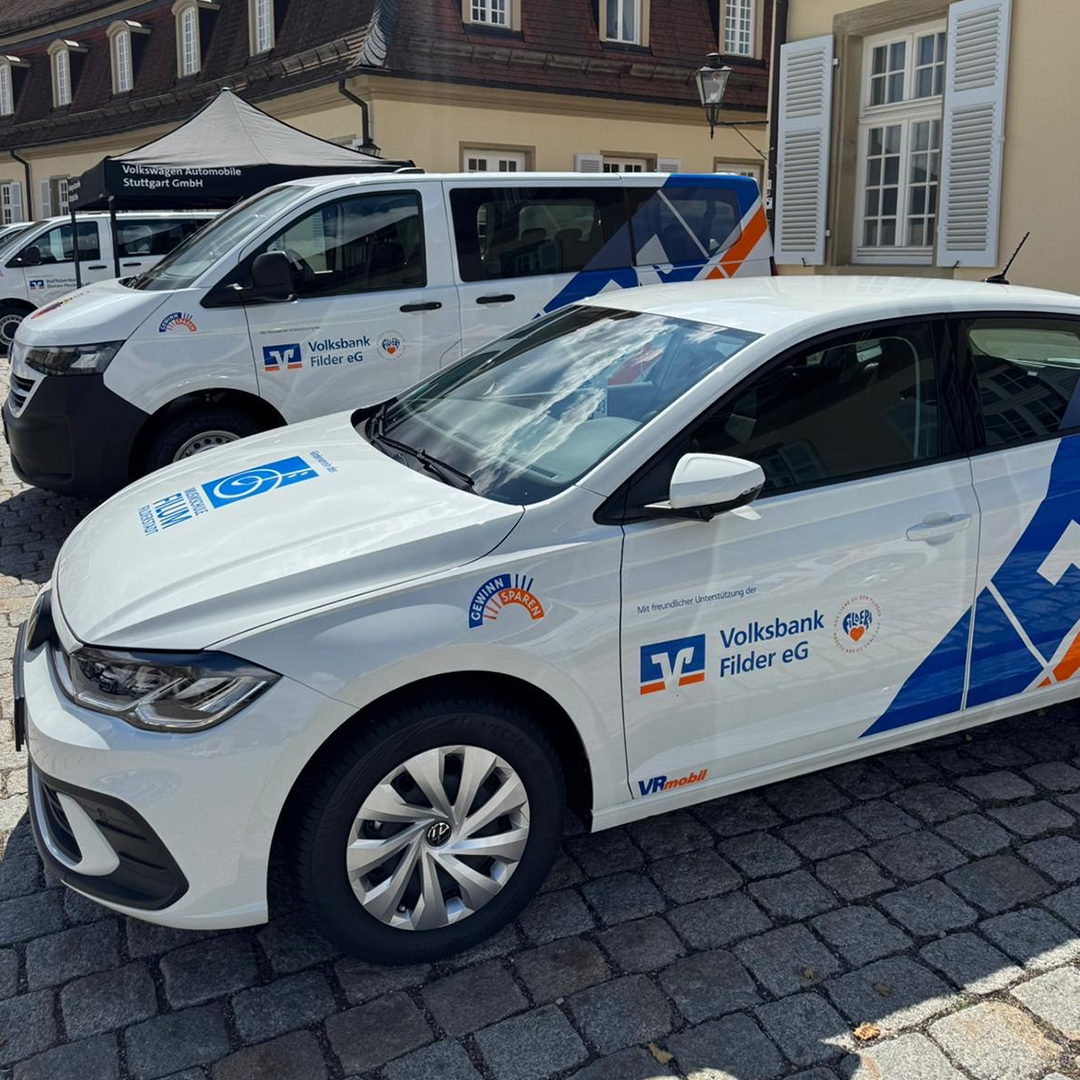 Ein weißer Firmenwagen der Volksbank Filder mit dem Logo der Volksbank Filder und dem Logo Aus Liebe zu den Fildern mit einem orangenen Herz